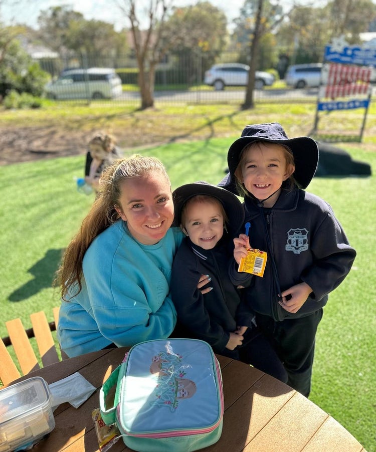 Students share a meal with family members at a picnic table during a school community lunch event, creating a warm and inclusive atmosphere where families can connect and enjoy time together.