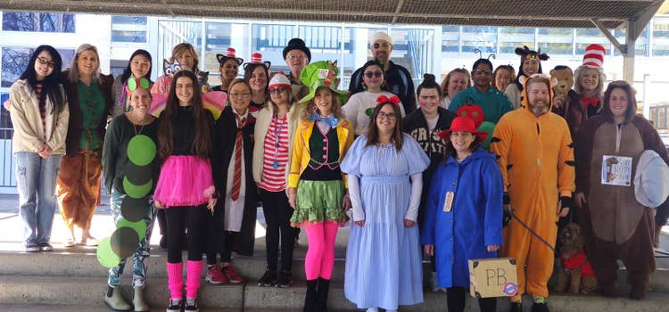 A large group of staff members pose together in colorful costumes, enthusiastically taking part in a whole school event and showcasing the school spirit at Cartwright Public School.