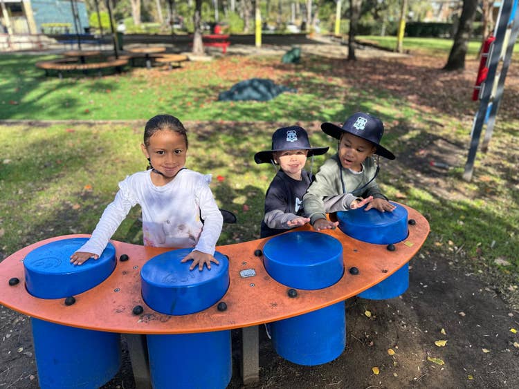 Children are seated together on a colorful playground structure, enjoying outdoor play as part of the ready-for-school Carter Club program that builds early literacy, numeracy, and social skills.